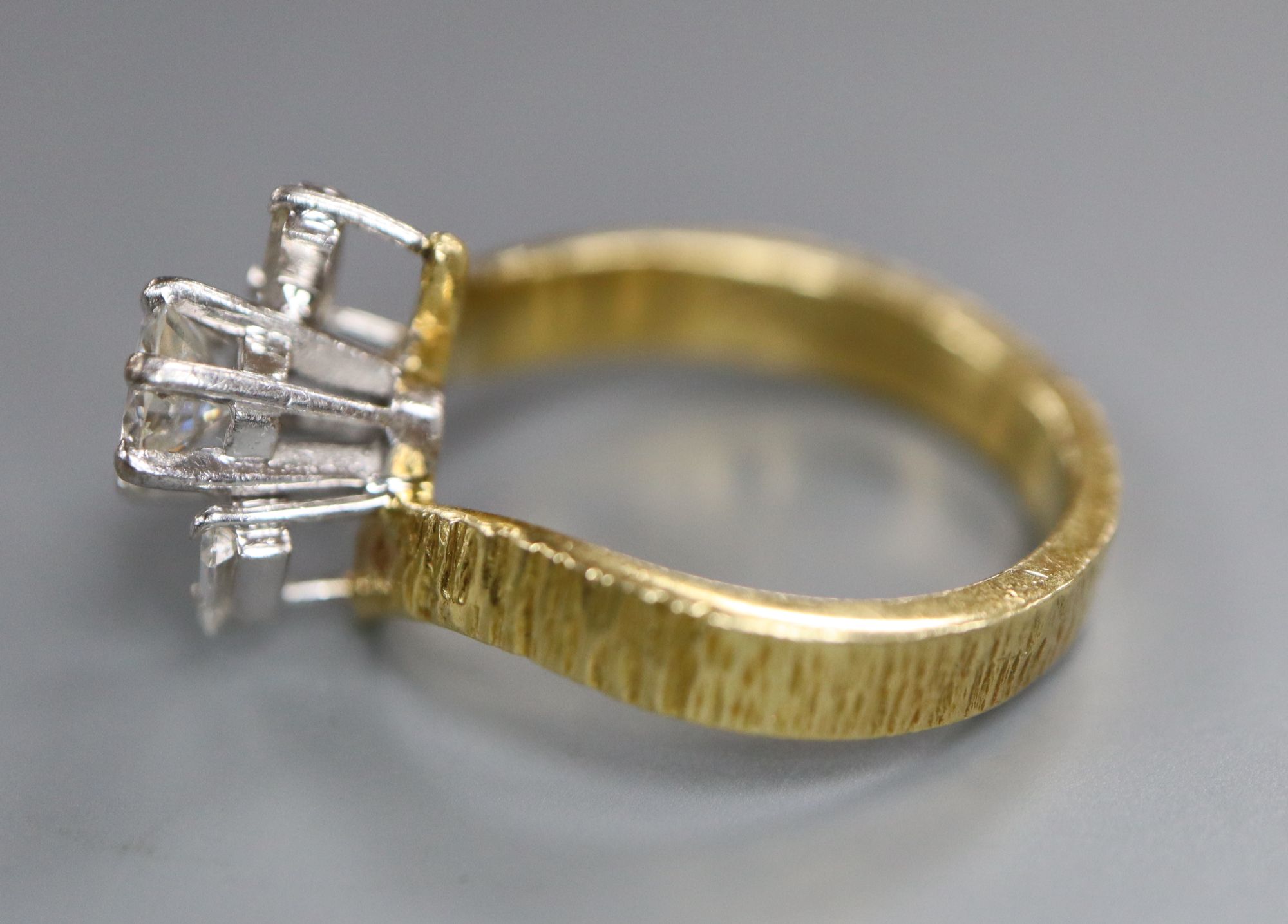A modern textured 18ct gold and single stone diamond ring, with baguette cut diamond set shoulders,